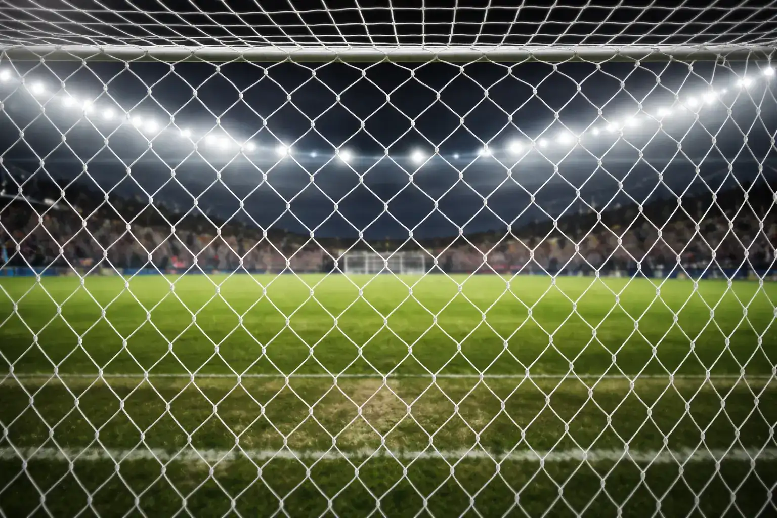Filet de but de soccer vu de l'intérieur avec la pelouse et les tribunes du stade en arrière-plan